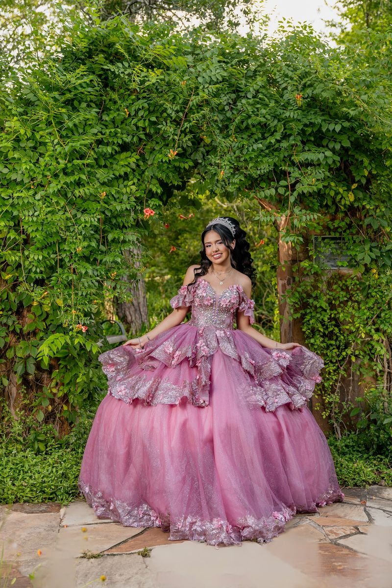 Quinceañera twirling her pink gown in a garden