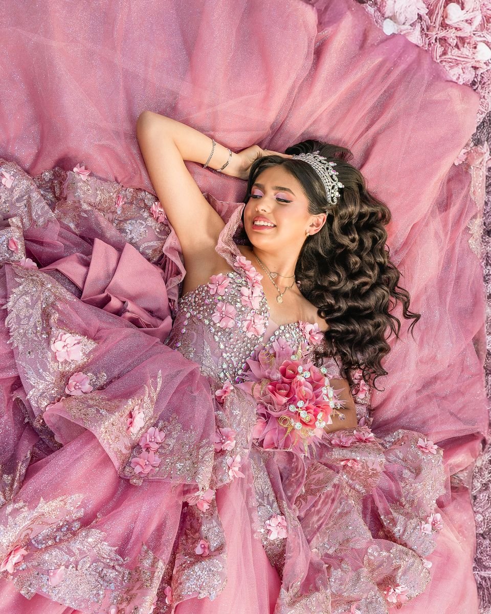 Quinceañera lying on her pink gown, seen from above